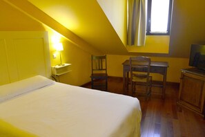 A room with a bed, a desk, a chair, a lamp, and a television. - Alda Vía León (León)