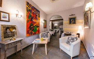 Un vestíbulo de hotel con zona de comedor, que presenta un cuadro abstracto de gran tamaño, una estatua y una araña.