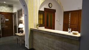 A hotel reception area with a reception desk, a clock, and a potted plant. - Alda Vía León (León)