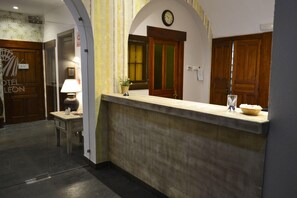 Un'area reception di un hotel, con una scrivania, un orologio e una pianta in vaso.