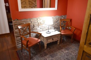 A room with a brick wall, two wooden chairs, a small table, and a patterned rug. - Alda Vía León (León)