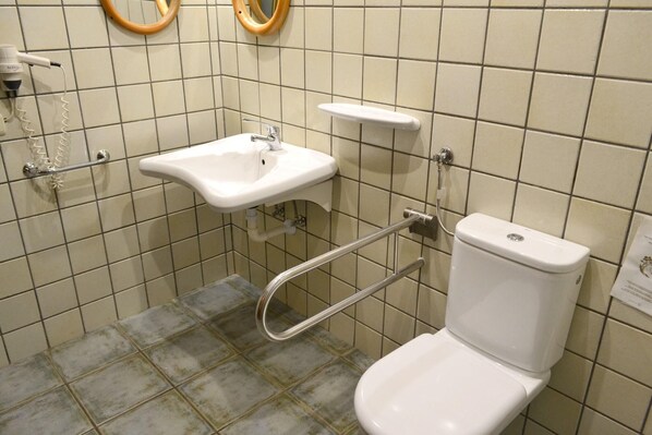 Ein Badezimmer mit einem weißen Waschbecken, einer Toilette und einem Händetrockner.