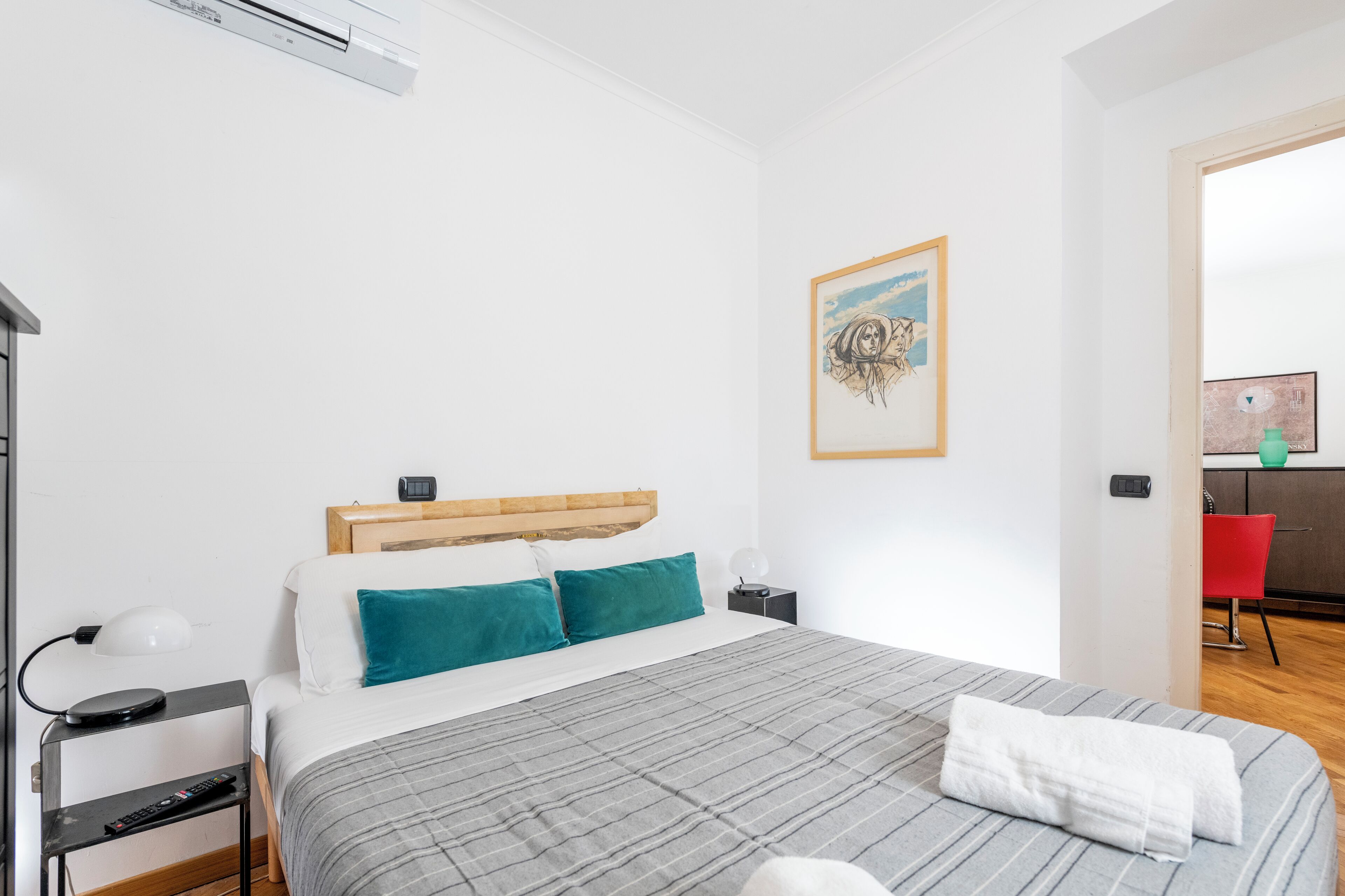 Ein modernes Hotelzimmer mit einem Bett, einem Nachttisch, einer Lampe und einem Bild an der Wand.