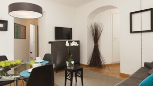 A modern living room with a dining area, a flat-screen TV, and a decorative plant. - Corso Vittorio Apartments (Rome)