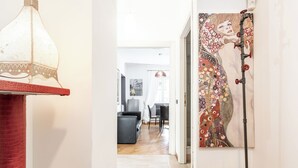 A hallway with a red textured wall, a hanging lamp, and a painting of a woman. - Corso Vittorio Apartments (Rome)