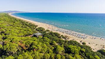Na praia, areia branca, espreguiçadeiras, guarda-sóis