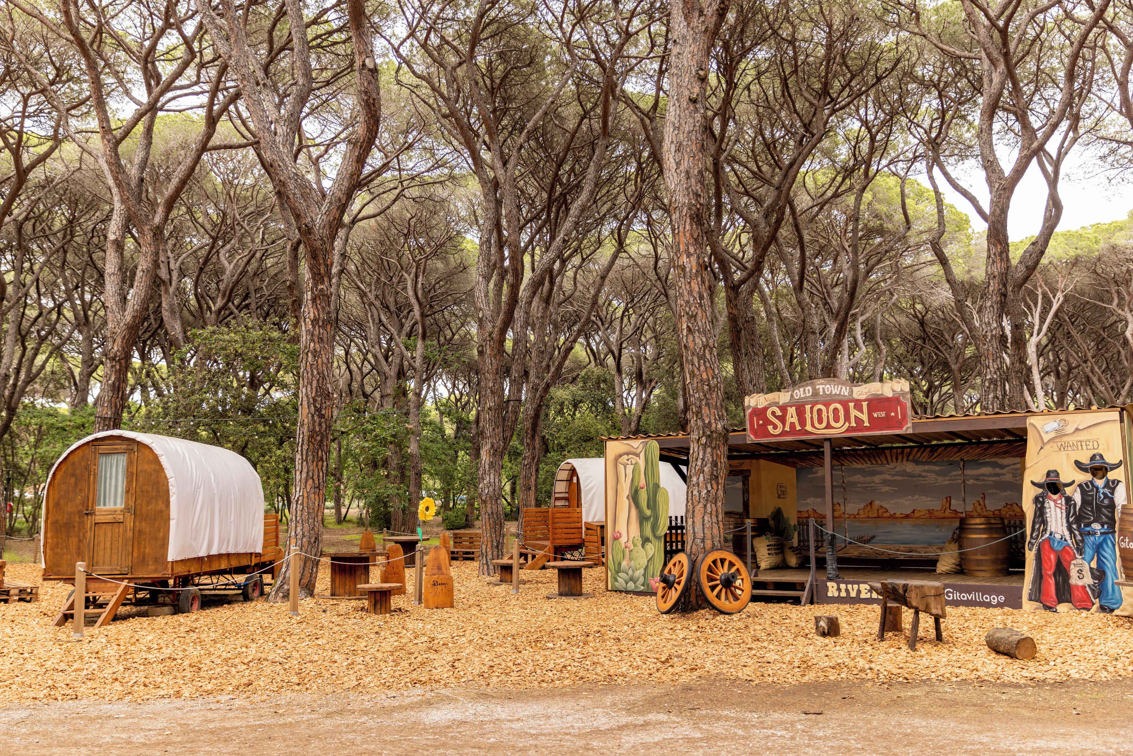A rustic campsite with wooden cabins and a saloon.