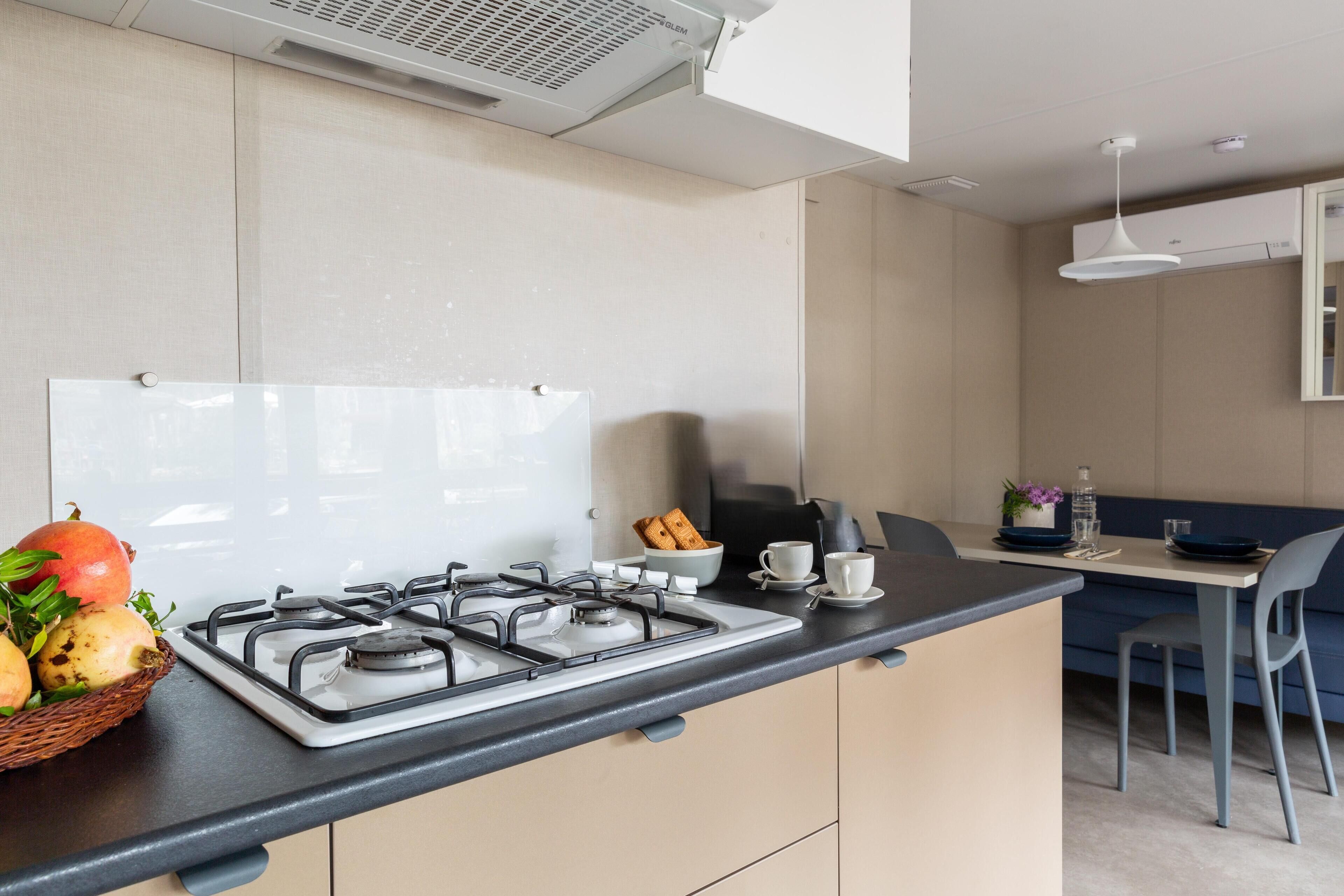 Een moderne keuken met een gasfornuis, een spoelbak en een eethoek met een tafel en stoelen.