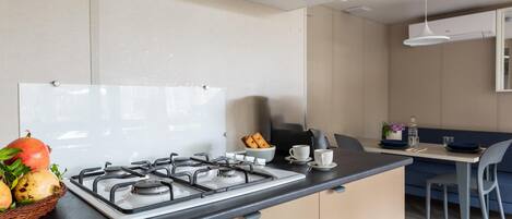 Ett modernt kök med en gasspis, en diskho och en matplats med ett bord och stolar.
