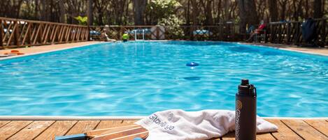 Eine Holzterrasse mit Pool, Handtuch und Wasserflasche.