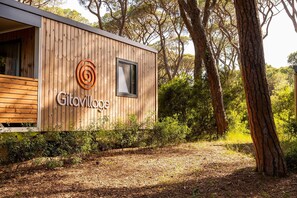 A wooden cabin with a window and a door, labeled 'Gilovillege,' surrounded by trees and a forested area. - Gitavillage Le Marze (Grosseto)
