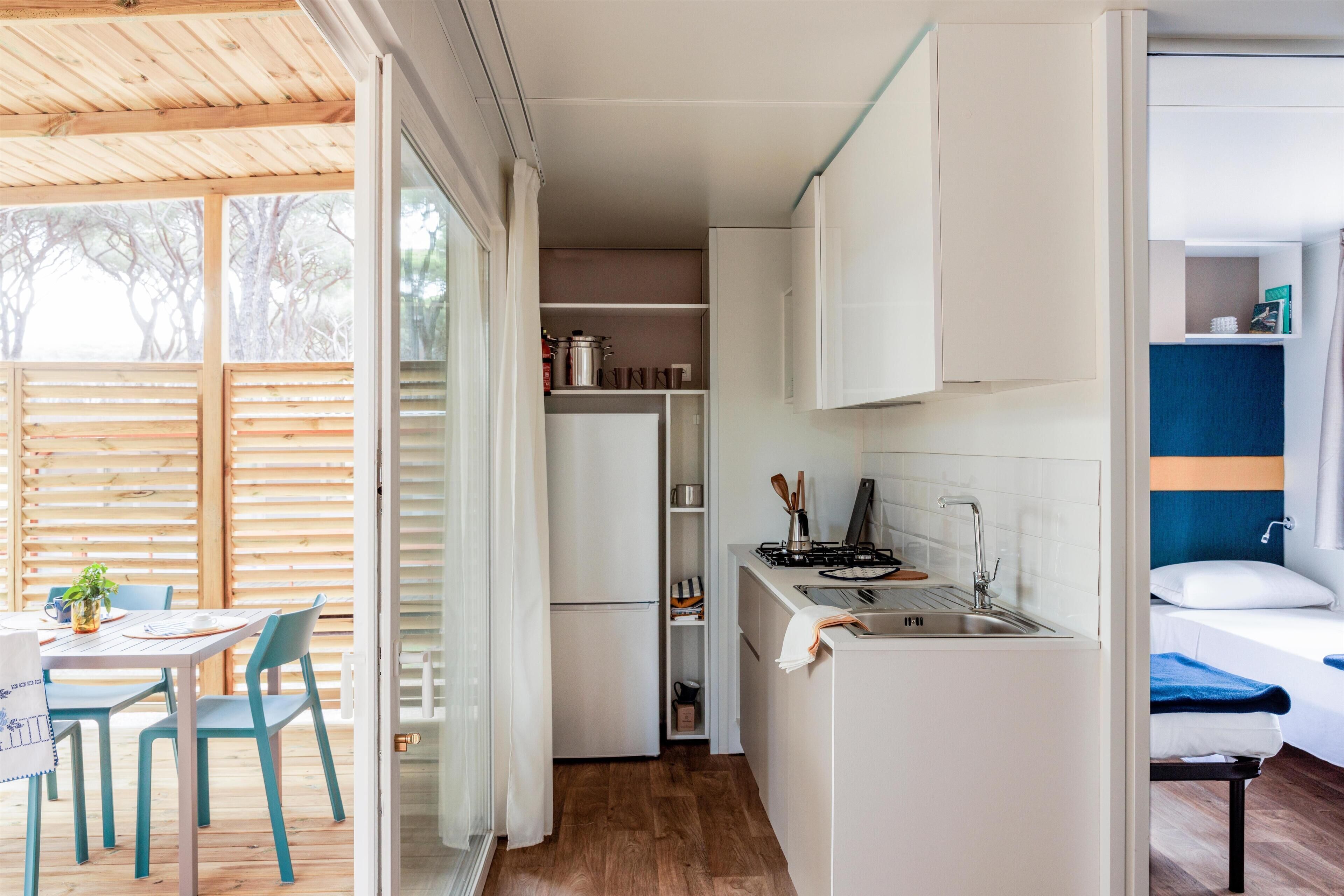 Una cocina compacta con armarios blancos, un lavamanos y una pequeña zona de comedor con sillas y una mesa.