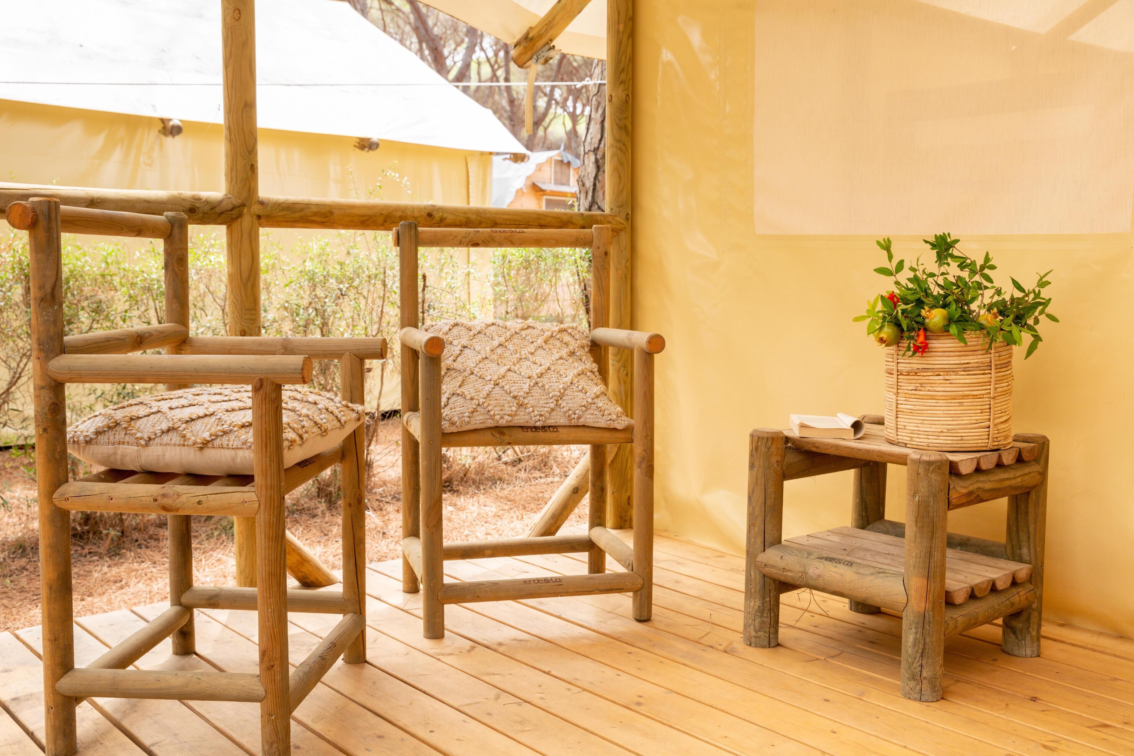 Una terraza de madera con dos sillas y una mesita con una cesta de plantas tejidas.