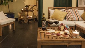 Een gezellige zithoek met een houten tafel gedekt voor een maaltijd, met een fles wijn, glazen en verschillende soorten kazen en vleeswaren.