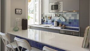Een moderne keuken met een groot eiland, roestvrijstalen apparatuur en een blauwe betegelde achterwand.