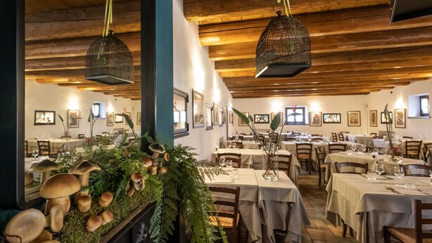 Een restaurant met houten balken en gedekte tafels.