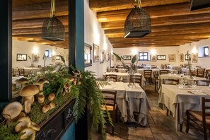 A restaurant with wooden ceilings and tables set for dining. - Residenza Napoleone (Rivoli Veronese)
