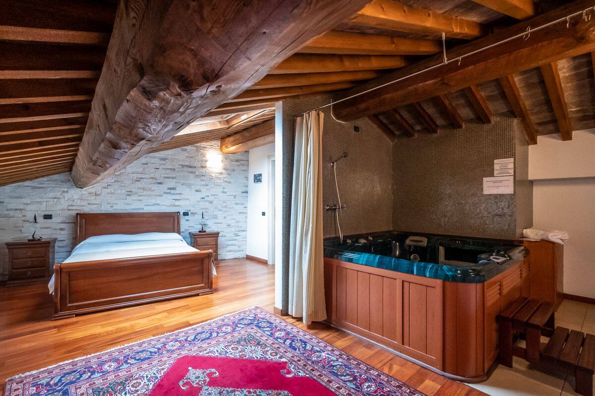 A bedroom with a wooden bed, a hot tub, and a patterned rug.