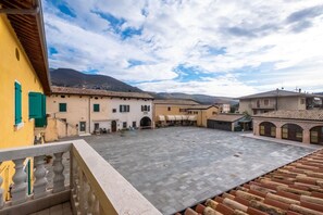 A courtyard with buildings, a stone floor, and a view of mountains. - Residenza Napoleone (Rivoli Veronese)