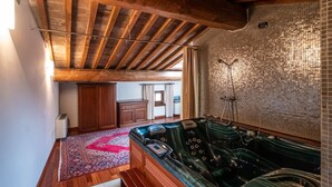Een wellnessruimte met een houten plafond, een mozaïekwand en een whirlpool.