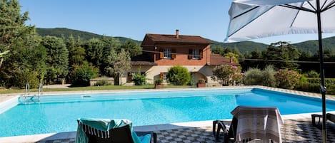 Una piscina al aire libre de temporada, sombrillas