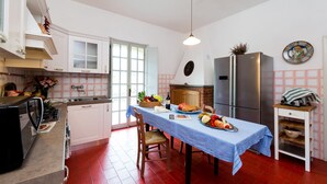 A kitchen with a dining table set for a meal, a refrigerator, and a sink.