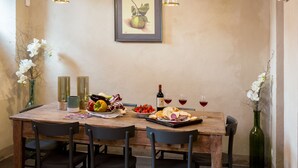 A wooden dining table with chairs, a framed picture on the wall, and a bottle of wine on the table. - Villa Torricella (Magione)