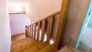 A wooden staircase with a handrail, leading to a room with a white ceiling and a light fixture. - Casale Pietrenta (Cortona)