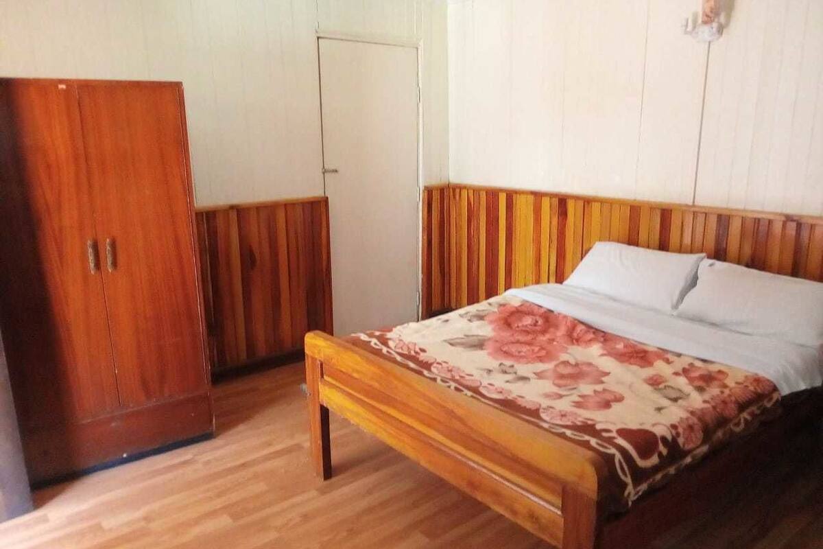 Un dormitorio con cama de madera, un armario y una puerta.