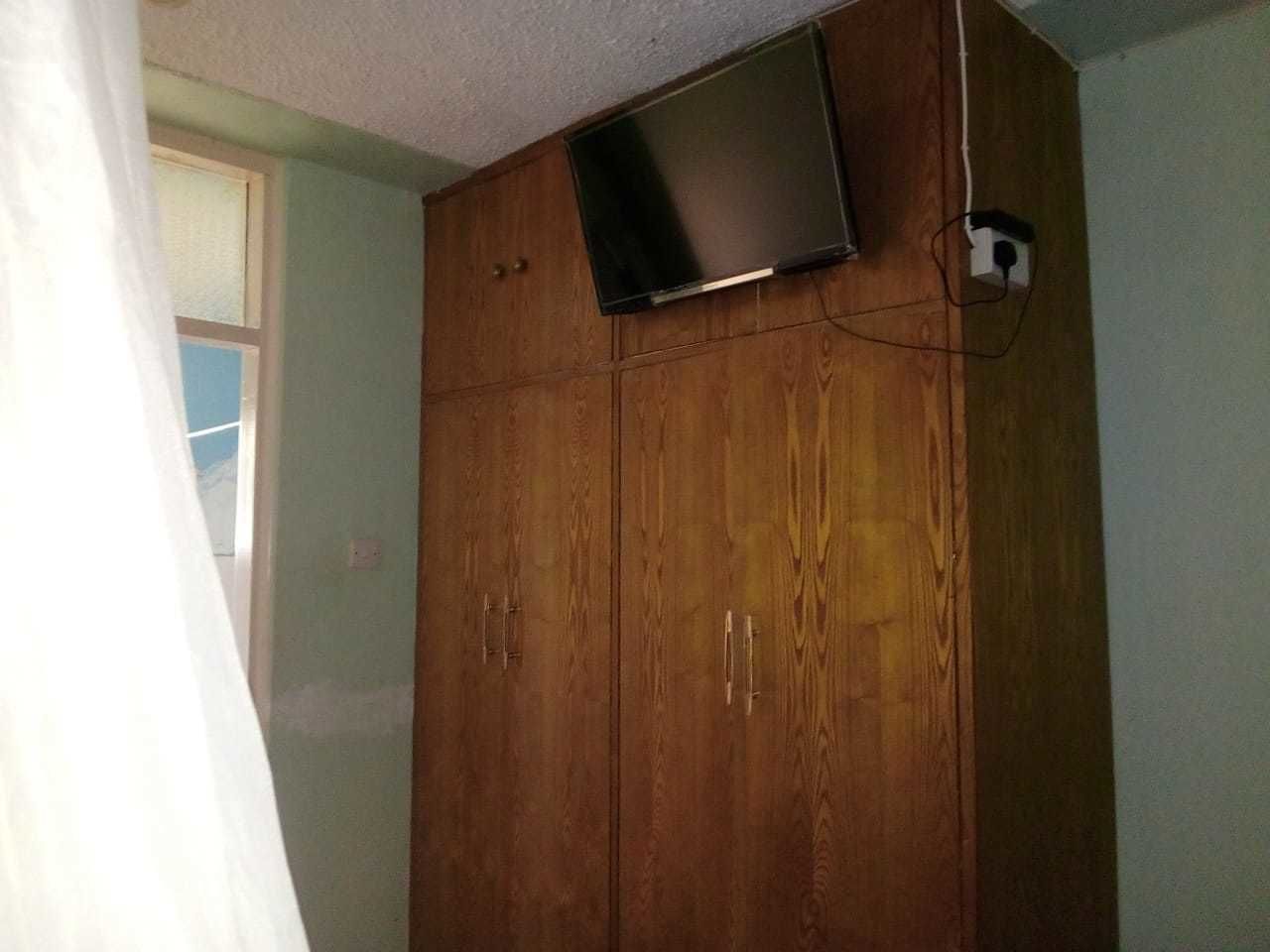 A wooden wardrobe with a flat-screen TV mounted above it.