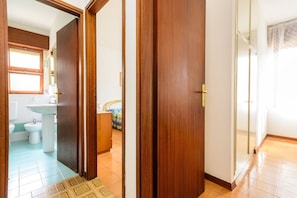 A hallway with wooden doors, a bathroom with a sink and toilet, and a patterned floor.