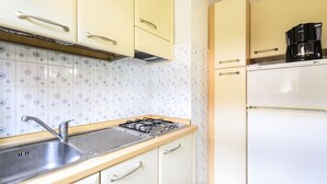 Eine Küche mit Gasherd, Spüle und Kaffeemaschine auf der Arbeitsplatte.