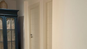 A hallway with a dark blue cabinet and two white doors. - Doneduà (Vico Equense)