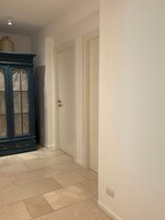 Un pasillo con un armario azul oscuro y dos puertas blancas.