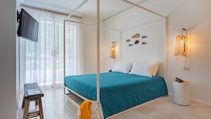 A bedroom with a four-poster bed, a television on the wall, and a small stool. - Doneduà (Vico Equense)