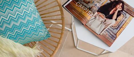 A magazine on a table, a wicker chair with a cushion, and a tiled floor.