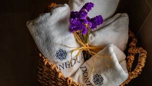 A woven basket containing a white cloth with embroidered text and purple flowers. - Doneduà (Vico Equense)