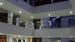 A multi-level atrium with a central staircase, railings, and seating areas. - Hotel Pooja International (Davanagere)