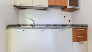 Una cocina moderna con gabinetes blancos, encimera de granito, electrodomésticos de acero inoxidable y microondas integrado.