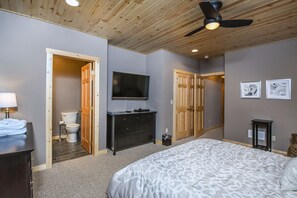 Un dormitorio con cama, cómoda, televisor y ventilador de techo.