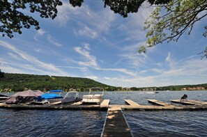 A lakeside dock with boats, a covered area, and a view of a hilly landscape. - Hartwood Village 3 Bedroom Townhome #05 (McHenry)