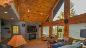 A cozy cabin interior with a fireplace, wooden walls, and comfortable seating.