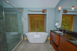 A bathroom with a glass-enclosed shower, a freestanding bathtub, wooden vanity, and a large mirror. - Hootenanny 5 Bedroom House (McHenry)