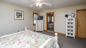 Ein Schlafzimmer mit Bett, Schminktisch, Kommode und Deckenventilator.