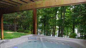 Un bain à remous avec vue sur une forêt et un plan d’eau.