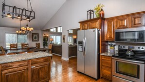 Una cocina amplia con armarios de madera, un refrigerador de acero inoxidable, un microondas y un horno.