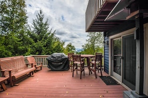 A wooden deck with a barbecue, a bench, and a table with chairs. - Bluebird Daze 4 Bedroom House (McHenry)