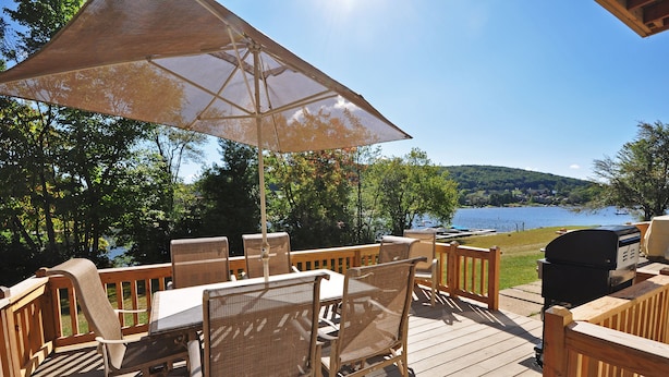 Eine Holzterrasse mit Gartenmöbeln, darunter ein Tisch, Stühle und ein Grill.