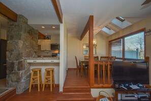 Un salón amplio con una pared de acento de piedra, muebles de madera y un televisor de pantalla plana grande.