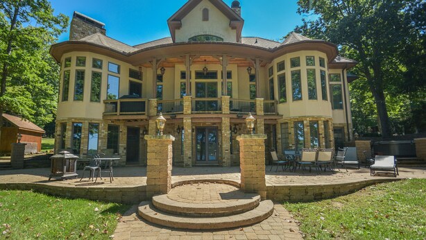 A large, two-story house with a central courtyard, stone columns, and a covered patio area.